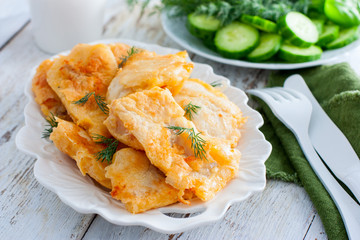 Pollock fillet in batter on a white plate, selective focus