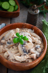 Stroganoff with chicken and mushrooms in a wooden bowl, selective focus