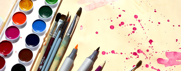 Supplies for drawing. Watercolor paints brushes pencils watercolor markers on a light background with purple blots. Copy space. Banner.