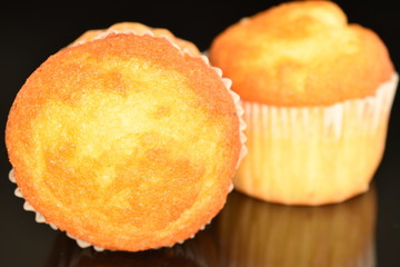 Fresh tasty muffins, close-up, on a black background.