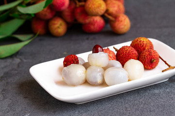 Lychee with leaves on gray background. Tropical fruit.
