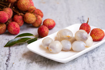 Lychee with leaves on gray background. Tropical fruit.