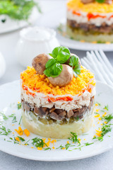 Beautiful festive layered salad with chicken, potatoes, carrots, pickles and fried champignons, selective focus