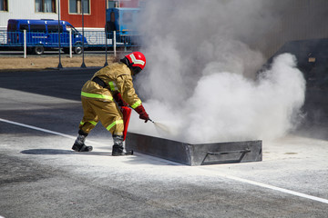 Extinguishing a major fire. A professional fireman in a special suit extinguishes an open fire with...