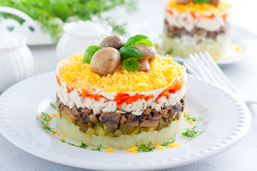 Beautiful festive layered salad with chicken, potatoes, carrots, pickles and fried champignons, selective focus