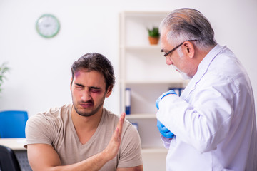 Obraz premium Young face injured man visiting experienced male doctor traumato
