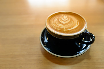 Beautiful of Latte art coffee in black cup on wooden table