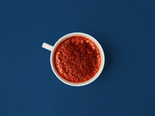 Red beetroot smoothie in a white mug with a pen on a blue background.