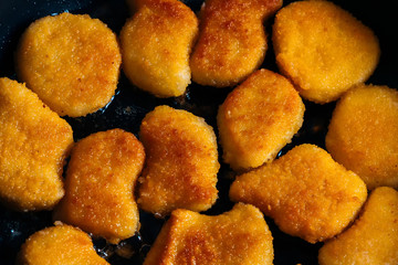 Chicken nuggets fried in a pan with butter