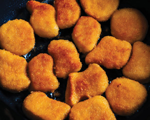 Chicken nuggets fried in a pan with butter