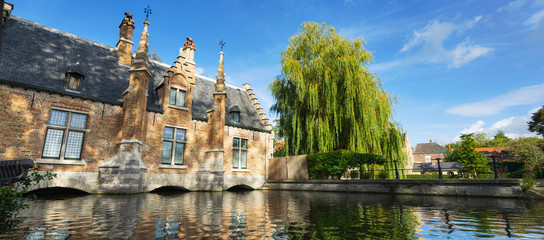 Fototapeta na wymiar Beautiful ancient building and tree at the canal in Brugge. Belgium. Banner edition.