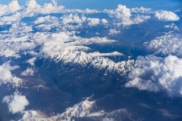 Aerial view of snowy Alps mountains with clouds..