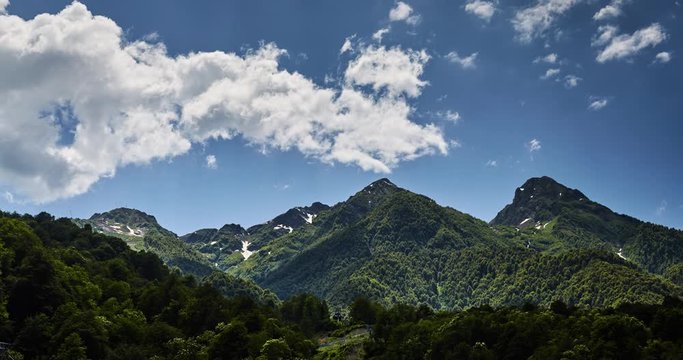 Time-lapse of clouds over mountains in Krasnodar region, Krasnaya Polyana, Sochi, Russia, a clear sunny weather, clouds float on the green mountains, leaving under itself shadows, peaks of mountains