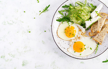 English breakfast - fried eggs, feta cheese, cucumber and arugula. American food. Top view, overhead, copy space