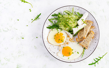 English breakfast - fried eggs, feta cheese, cucumber and arugula. American food. Top view, overhead, copy space