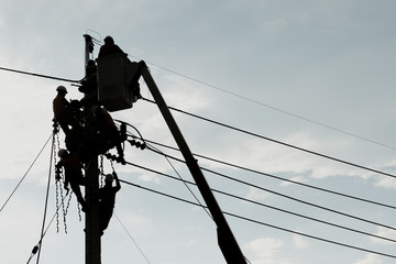 Electrician worker climbing electric power pole to repair the damaged power cable line problems...