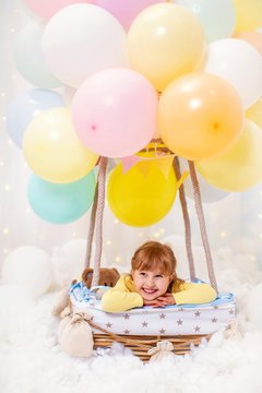 smiling little girl is sitting in basket decorative balloon