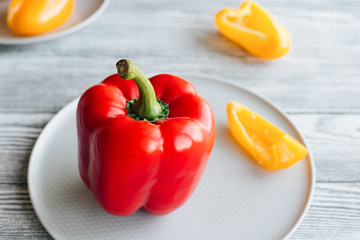  Red and yellow bell peppers on a white wooden background