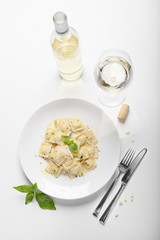 Ravioli with basil and parmesan on a white plate. White wine. Italian Cuisine