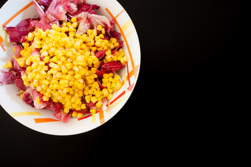 Salad with corn on black table, top view