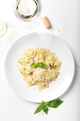 Ravioli with basil and parmesan on a white plate. White wine. Italian Cuisine