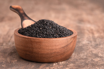 black Sesame close up shot on wood background. sesame seeds in a wooden spoon on dark table