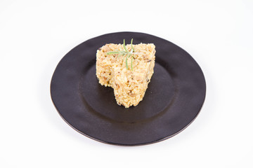 Heart shaped portion of Risotto with button mushroom and bacon decorated with rosemary twig on a black plate on a white background
