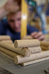 A male carpenter works with a tree in a carpentry shop. Making a mock-up of a log house.