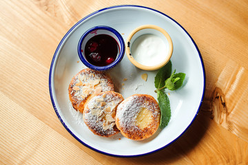 Cheesecakes with sugar powder and jam on a plate. Top view of tasty breakfast.