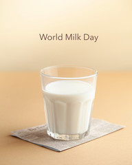  Glass cup with milk on a brown background with the inscription Milk Day. June 1st milk concept. Copy space.
