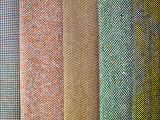 Vertical samples of natural fabrics in pastel colors close-up. Large assortment of fabrics in the store. Exhibition sample on the shop window