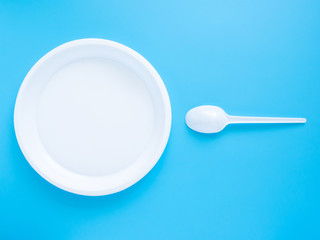 White plastic plate and spoon on a blue background. Conception of fertilization, pregnancy and contraception. the winner's sperm took the lead. Modern problems of conception and infertility