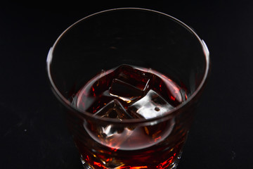 Glass with whiskey with ice on a dark background, isolate