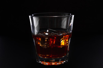 Glass with whiskey with ice on a dark background, isolate