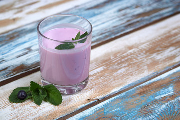 Glass cup with blueberry yogurt and mint on a wooden background. Healthy breakfast on a fine morning