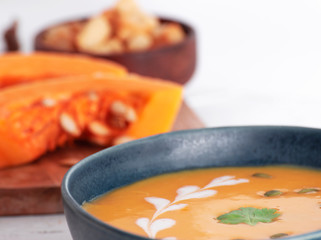 Homemade cream of pumpkin soup with sour cream sauce, 
croutons, and pumpkin seeds. White background.