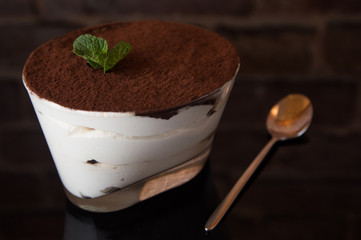 Tiramisu close-up on a black mirror background, with a spoon.