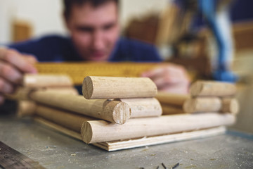 A male carpenter works with a tree in a carpentry shop. Making a mock-up of a log house.