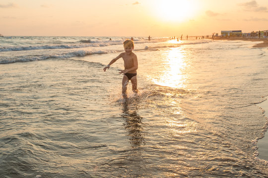 Boy running along the beach during sunset on the sea