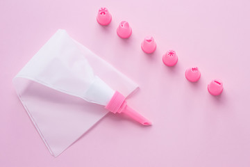 Cake decorating tools, the pastry bag with nozzles on pink background for cake decoration. Concept of cooking confectionery with cream.
