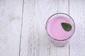 Glass cup with blueberry yogurt and mint on a light wooden background. Healthy breakfast on a fine morning