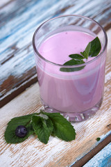 Glass cup with blueberry yogurt and mint on a wooden background. Healthy breakfast on a fine morning