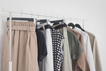 A rack with stylish clothes next to a white wall in the room. Clothing retails concept. Advertise, sale, fashion.