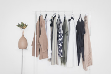 A rack with stylish clothes next to a white wall in the room. Clothing retails concept. Advertise, sale, fashion.