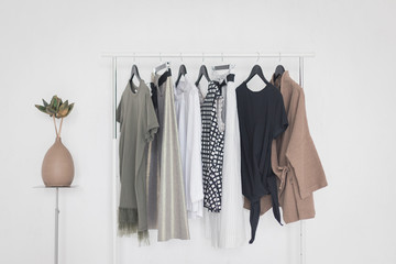 A rack with stylish clothes next to a white wall in the room. Clothing retails concept. Advertise, sale, fashion.