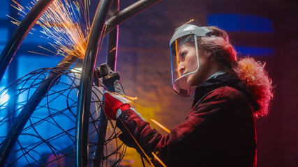 Young Contemporary Female Artist is Grinding Her Metal Tube Sculpture with a Handheld Power Tool in...