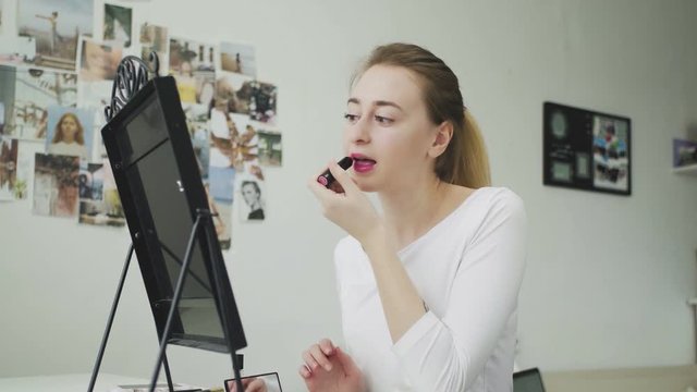 Woman applying lipstick. Young model putting on some makeup, using lipstick to color hel lips