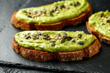 Healthy Homemade Avocado creamy Toast with nuts mix on rustic stone board