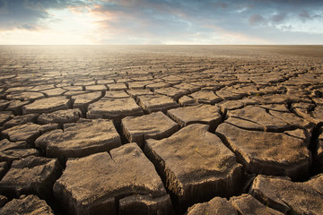 Dry cracked background ground with dramatic sunset sky global warming 