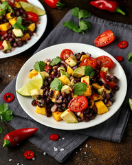 Avocado, mango salad with black bean on white plate